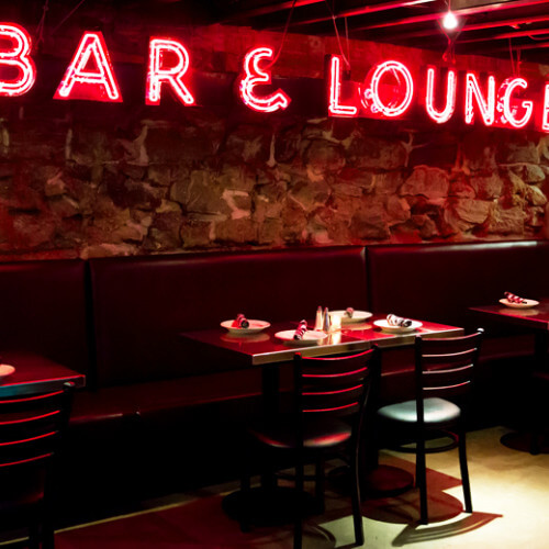 the boiler room tables chairs neon sign that reads bar and lounge