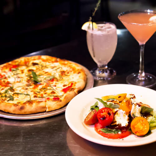 the boiler room pizza and caprese salad with cocktails