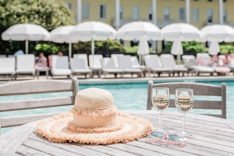 hat and wine glasses sitting by a pool
