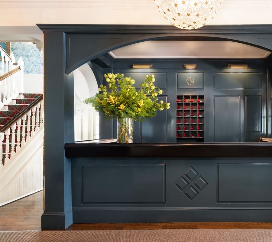 Front Desk at the Virginia Hotel, with a blue paint color and a vase of green and yellow flowers on top of the desk