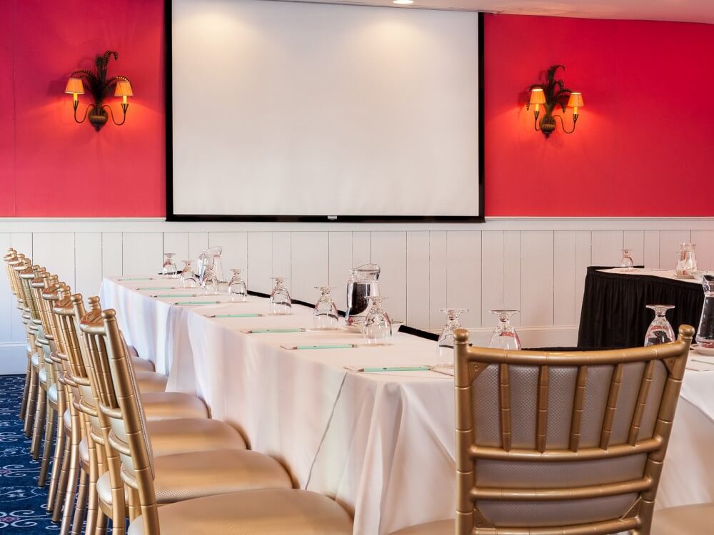 chairs arranged at a table with a projector screen in the background