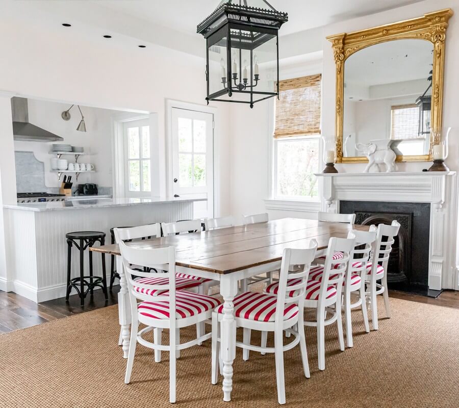 White Cottage dining room with white painted walls, red-striped chairs, white dining table and fireplace