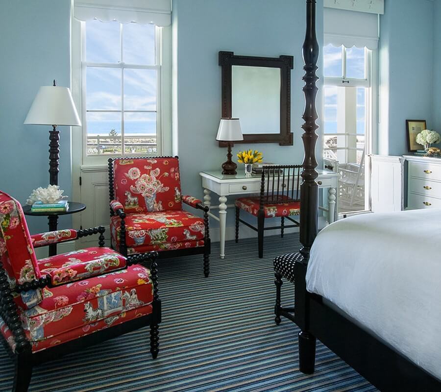 blue-painted guest room with red chairs and a bed